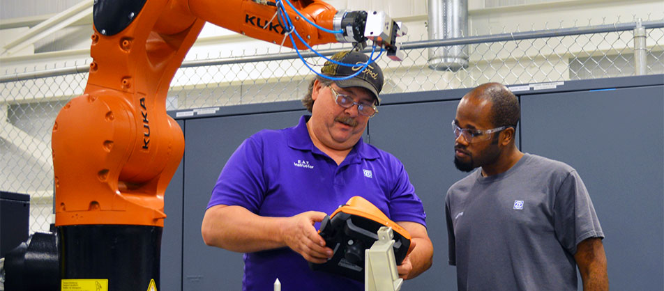 two men using remote control to run robotic arm